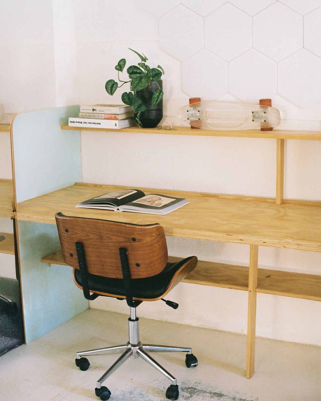A plywood desk and shelves built into the wall, with a timber office chair